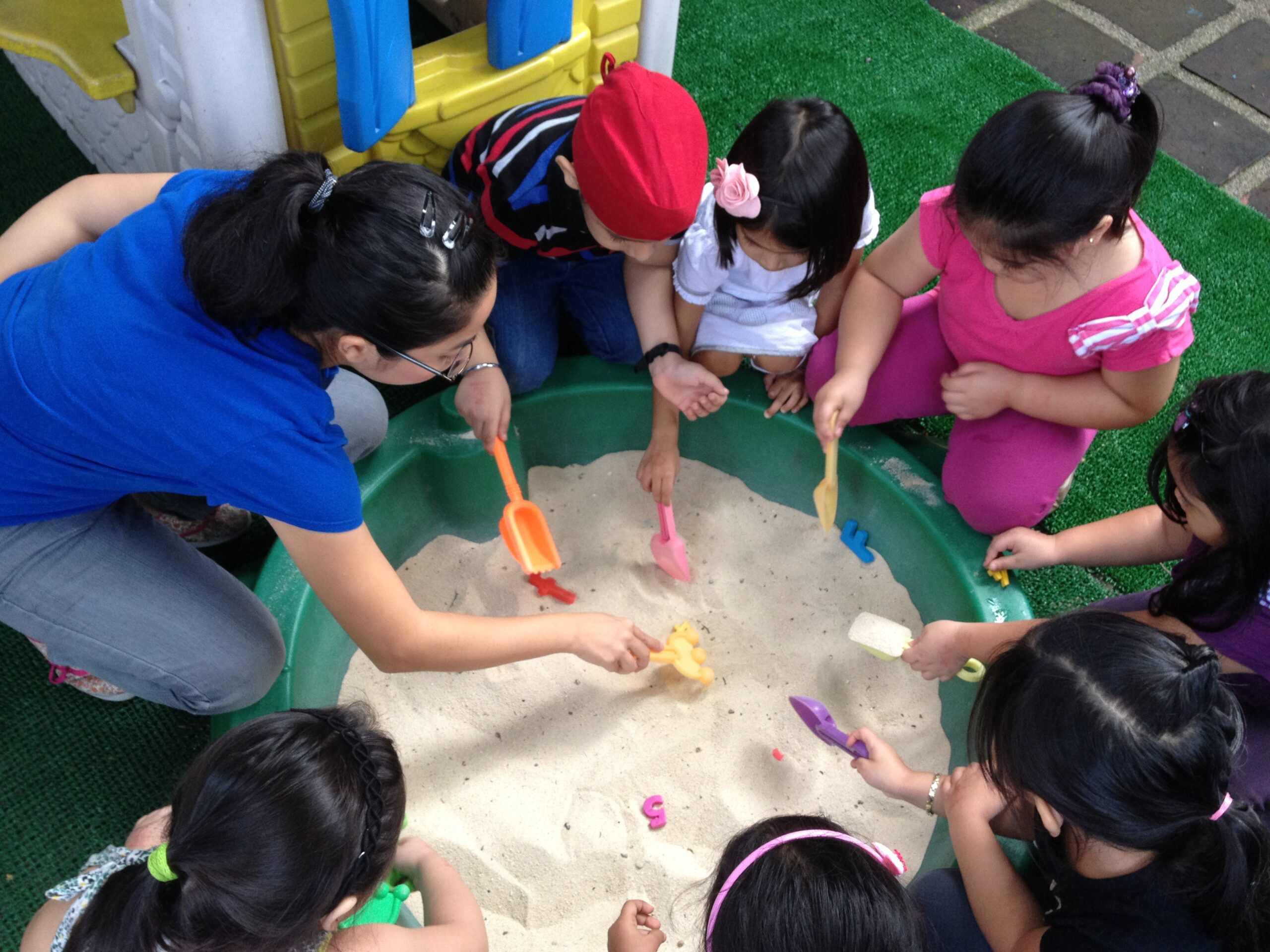 Preschool teacher and students making origami puppets